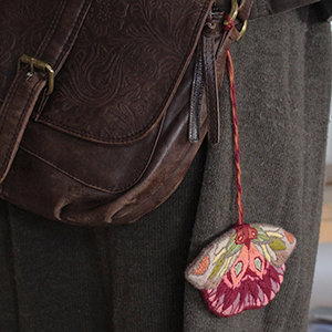 photo d'un papillon brodé accroché à un sac en cuir